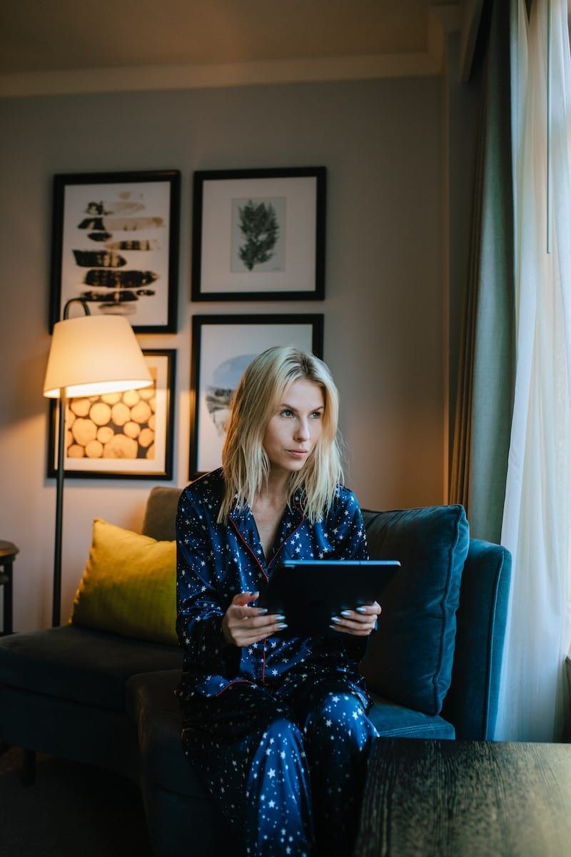 a woman sitting on a couch looking at a tablet