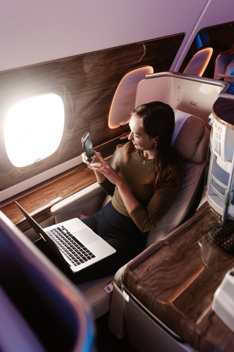 eine Frau, die in einem Flugzeug sitzt und auf ihr Handy schaut