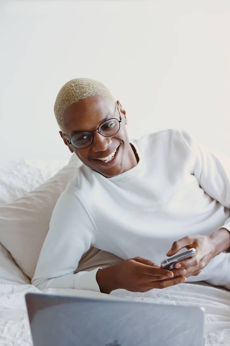 hombre con jersey blanco de cuello alto sosteniendo un smartphone