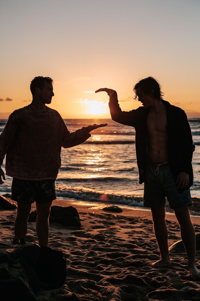 日落时分，两名男子在海滩附近握手的特写照片