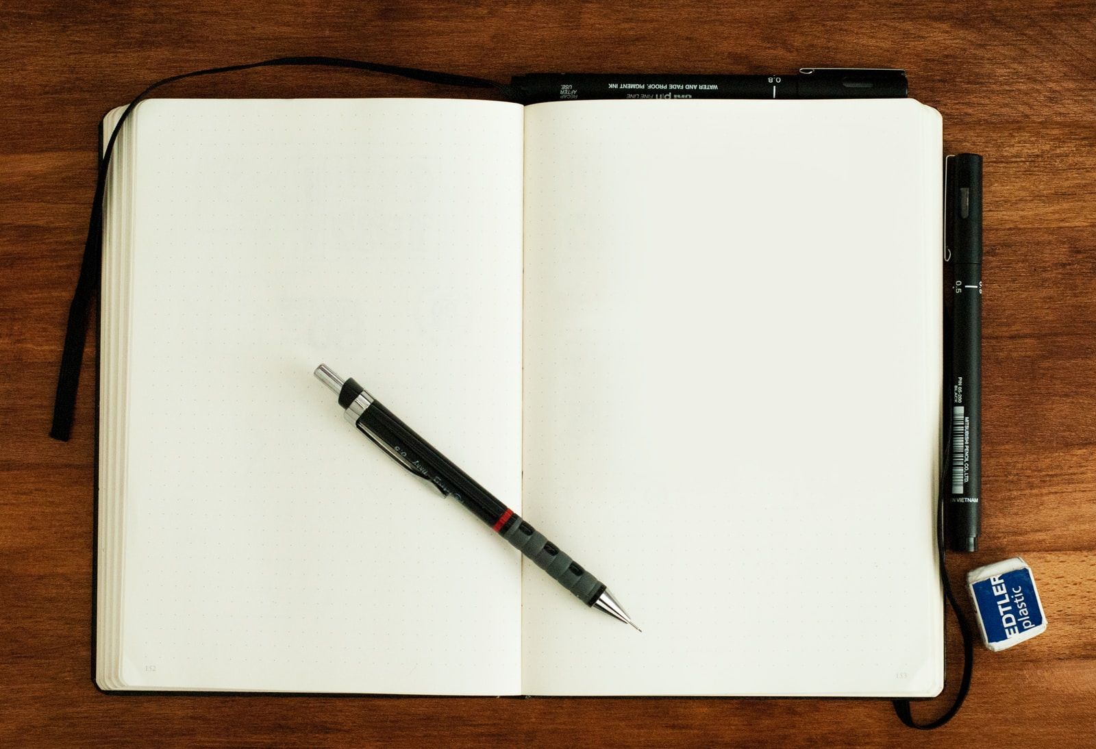 قلم قابل للسحب باللونين الأسود والفضي على كتاب فارغ