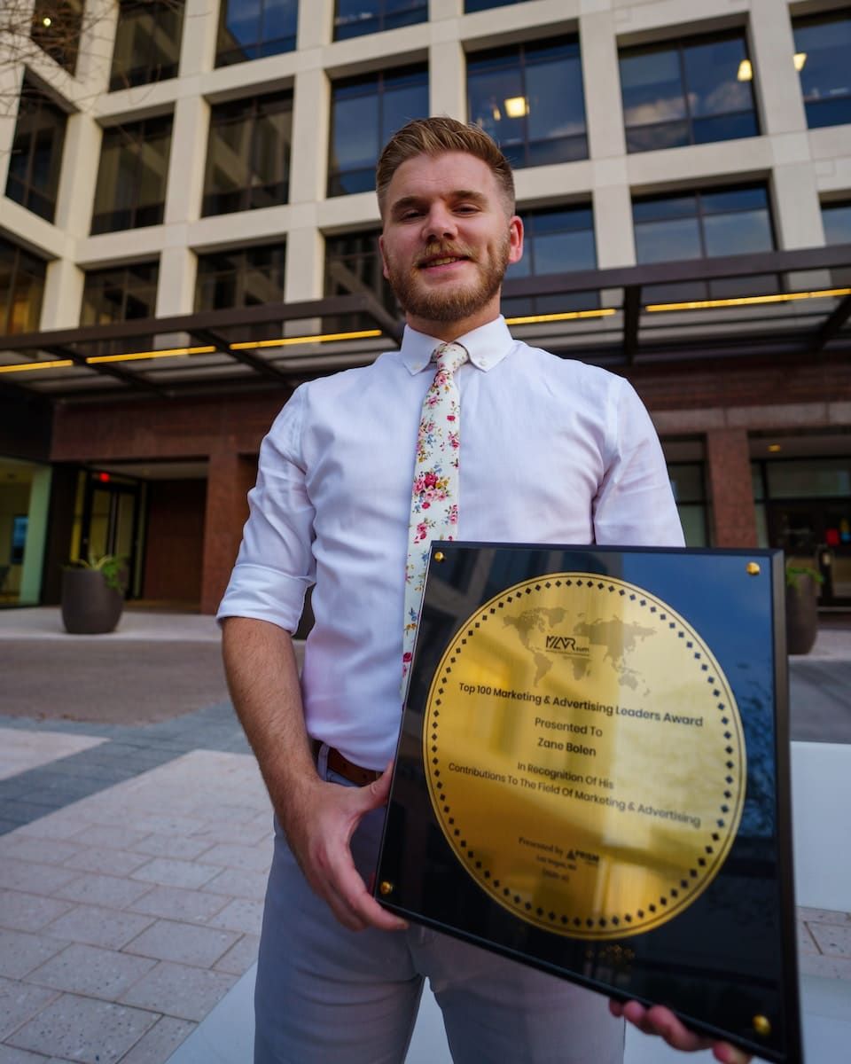 Mann in weißem Hemd mit Knopfleiste hält blauen und goldenen runden Rahmen