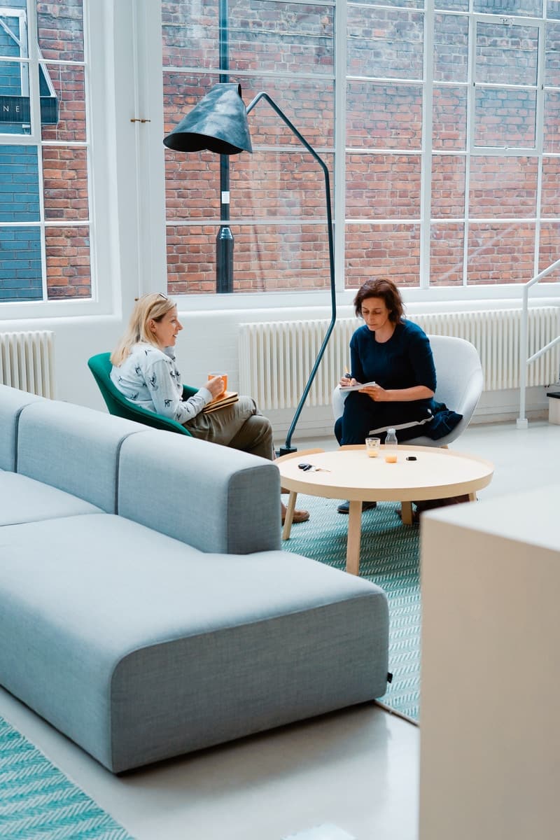 dos mujeres sentadas en sofas dentro de una casa