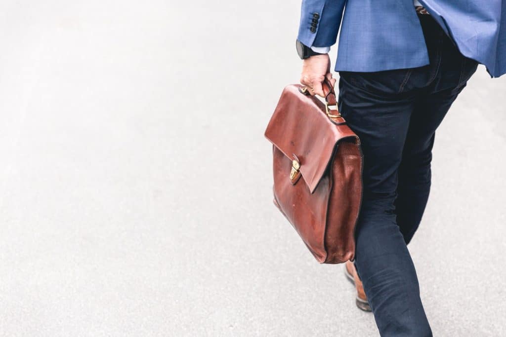 persona caminando con un bolso de cuero marrón en la mano