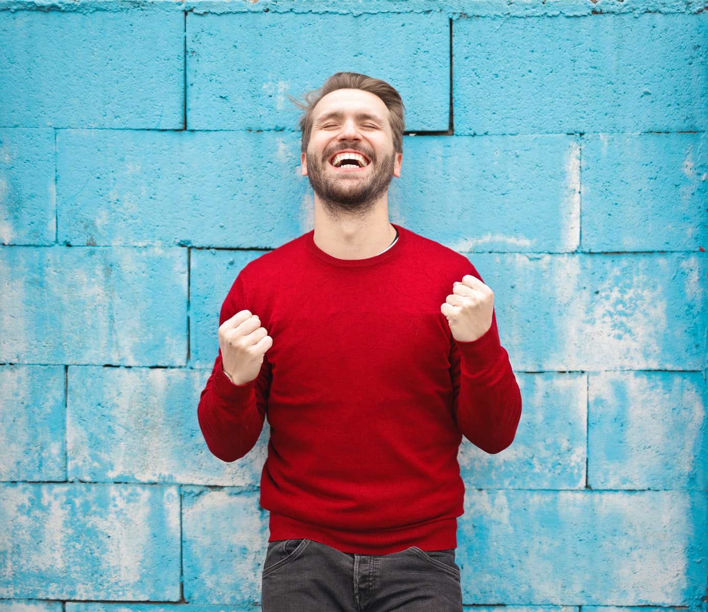 uomo con camicia rossa a maniche lunghe in piedi accanto al muro