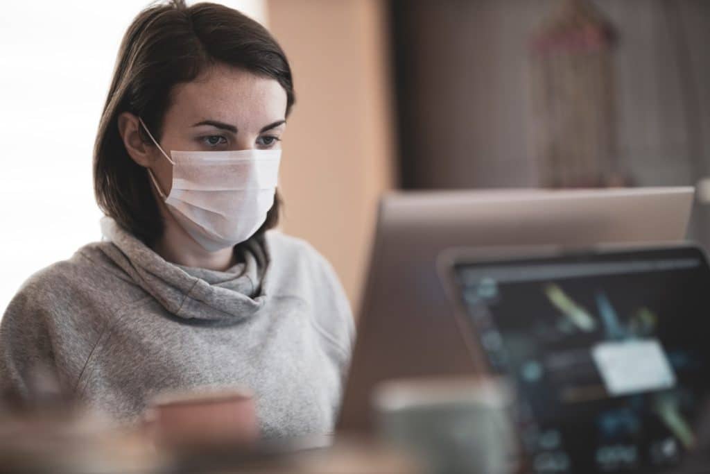 Frau mit grauem Kapuzenpulli und weißer Gesichtsmaske