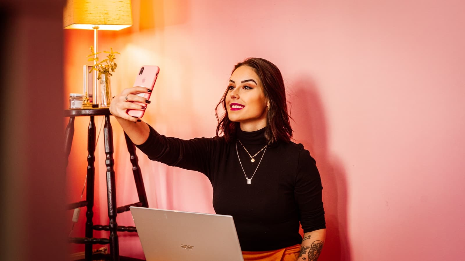 donna con camicia nera a maniche lunghe che tiene in mano uno smartphone bianco