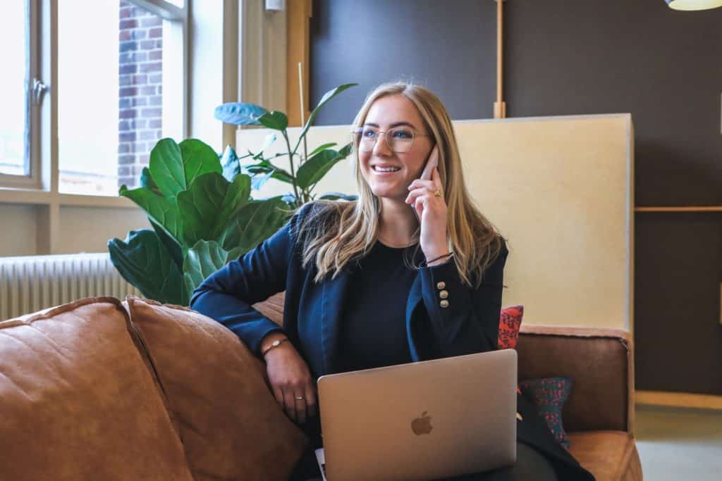 femme en chemise bleue à manches longues utilisant un macbook argenté