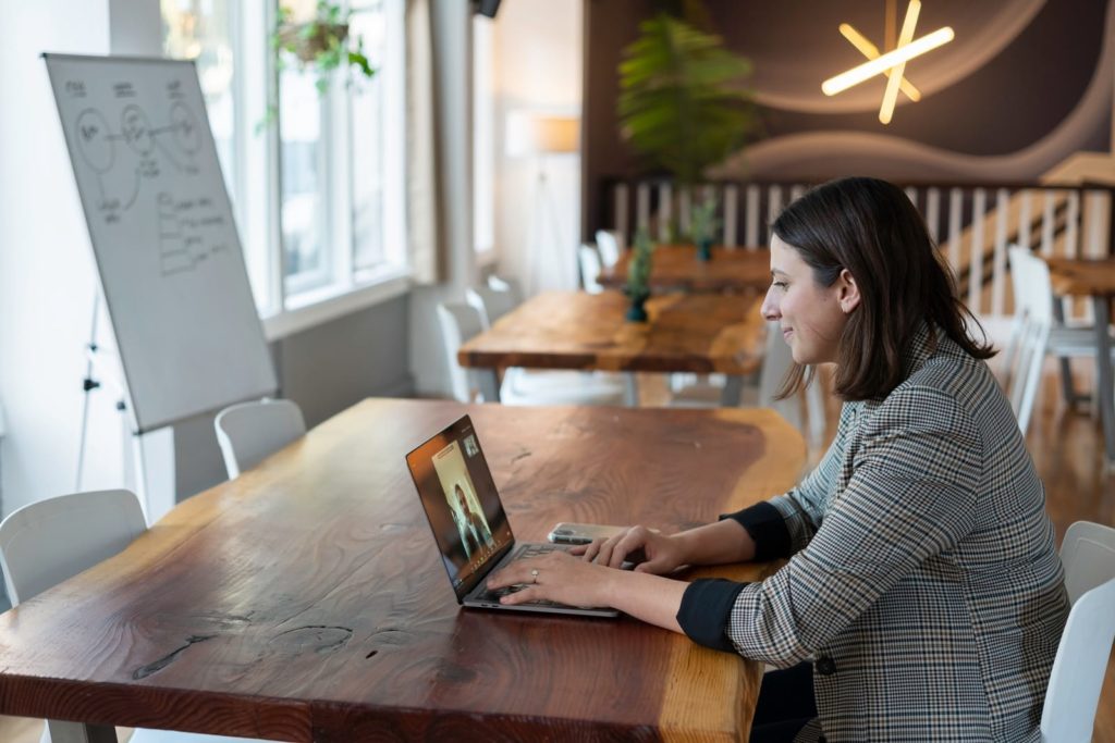 امرأة ترتدي قميصا بأكمام طويلة مخططة باللونين الرمادي والأبيض باستخدام جهاز MacBook فضي