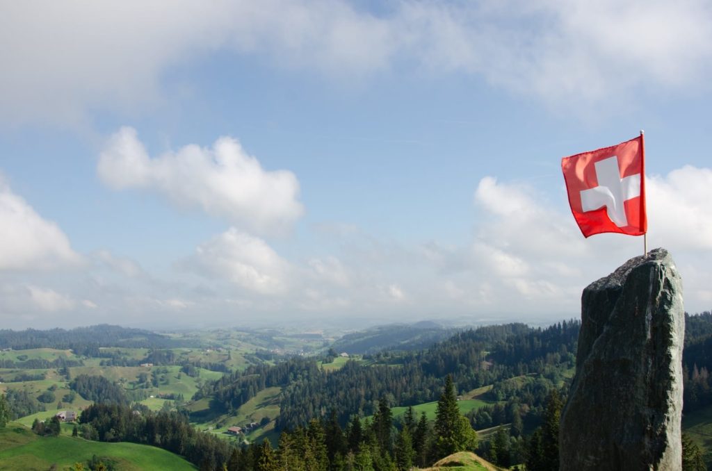 árvores verdes em uma montanha sob nuvens brancas durante o dia