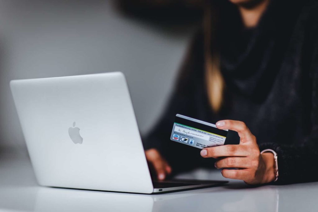 mulher segurando um smartphone preto perto de um macbook prata