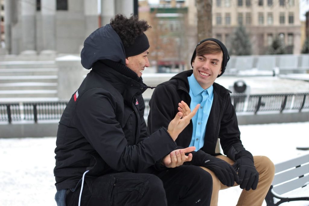 двое мужчин разговаривают, сидя на скамейке