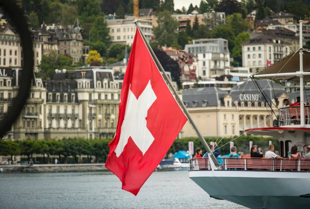 rot-weißes Segelboot auf dem Wasser in der Nähe von städtischen Gebäuden bei Tag